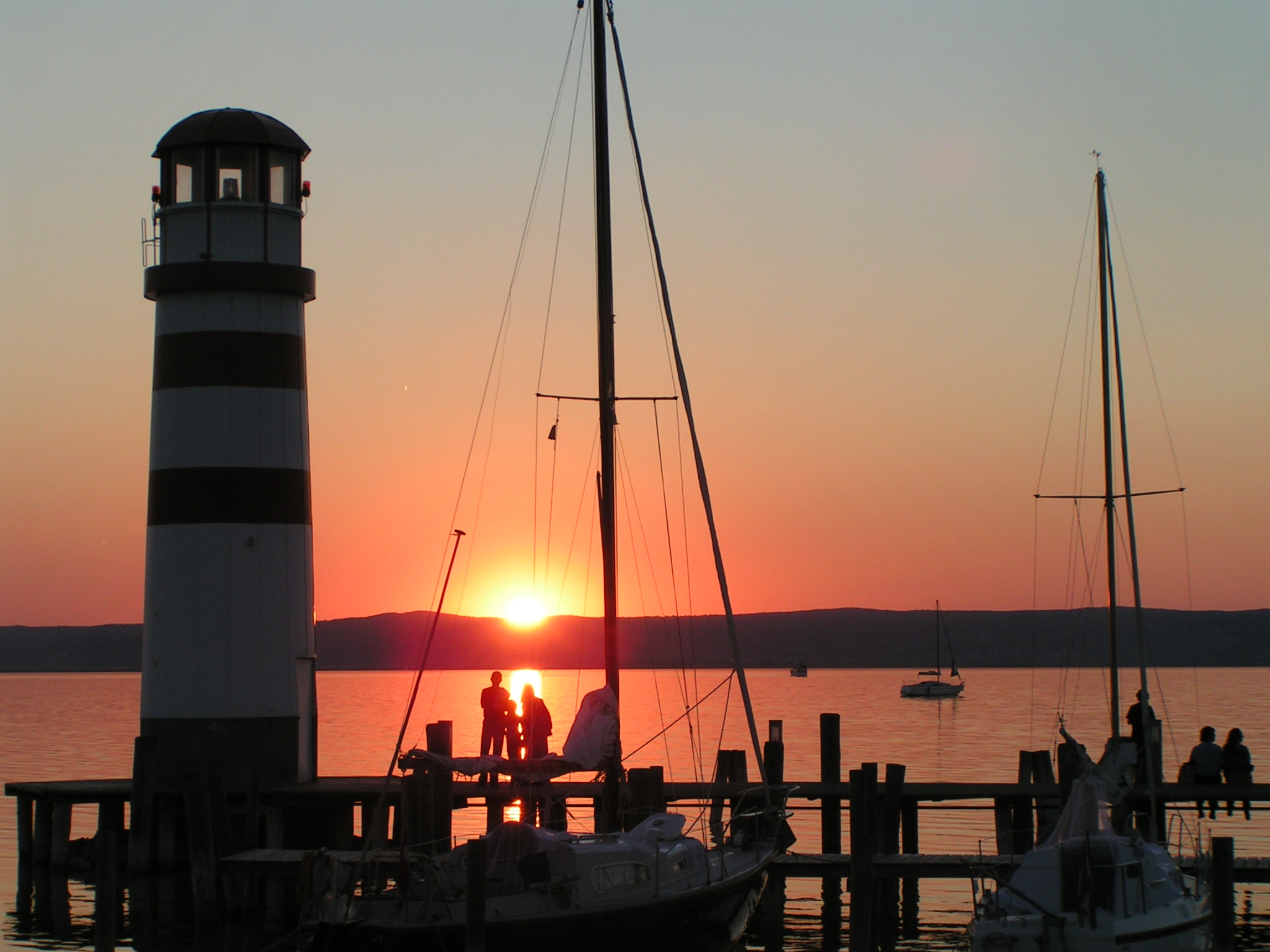 Sonnenuntergang am Hafen von Podersdorf mit Leuchtturm und Segelbooten