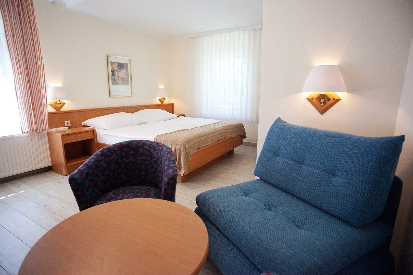 Schlafzimmer mit Doppelbett, Sessel und blauem Sofa